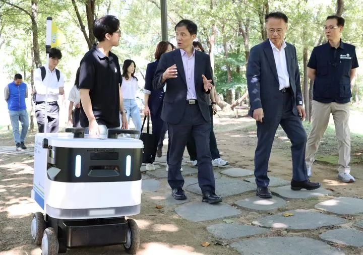 양수리 수풀로에서 배달 로봇과 함께 걷고 대화하는 사람들.